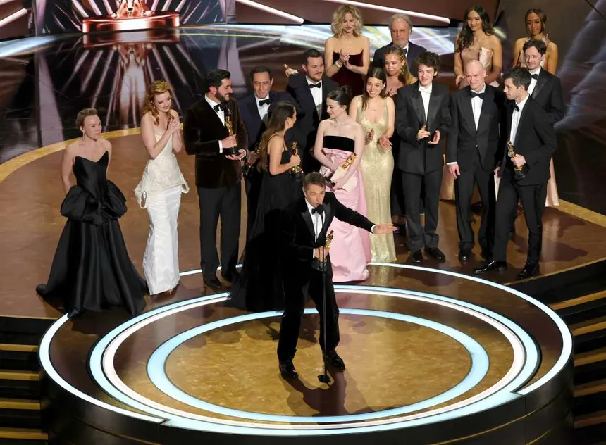 The cast and filmmakers of Anora accepting an award on stage at a ceremony