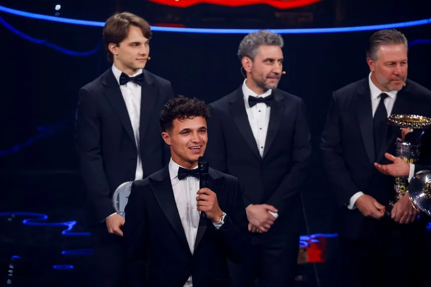 A tuxedoed award winner speaking into a microphone at a formal black-tie gala ceremony