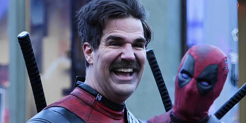 A mustached figure in a red-and-black Deadpool costume posing for the camera