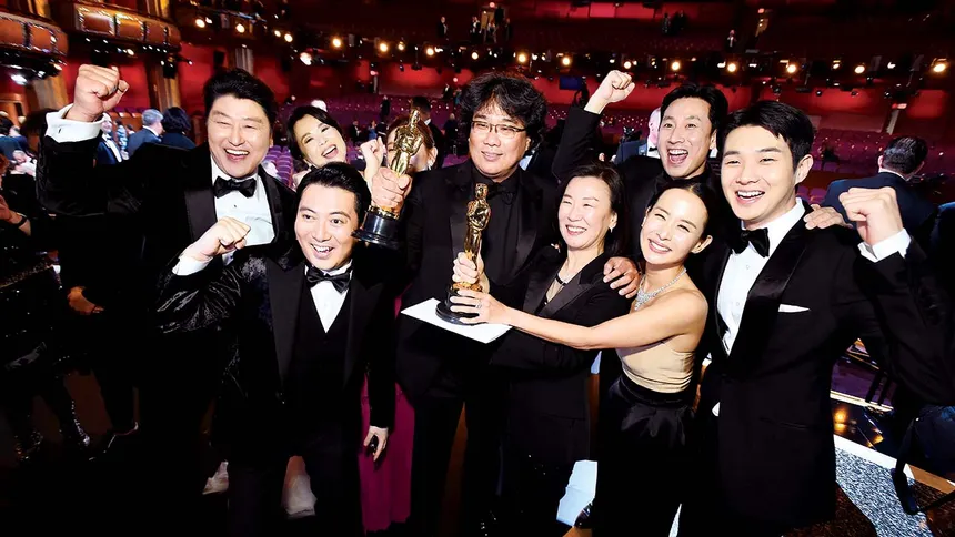 The cast and director of Parasite celebrating with their Oscars at the Academy Awards ceremony